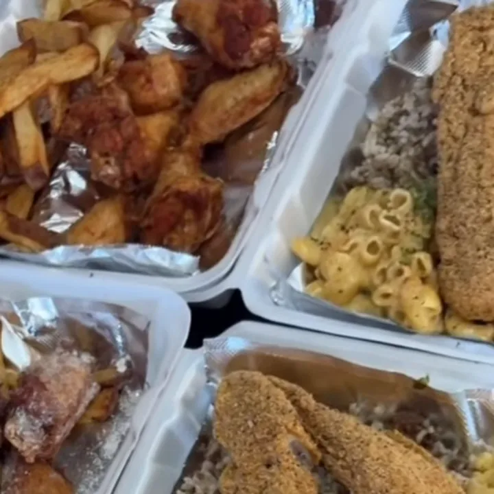 Takeout boxes with fries and wings, and a box of crusted fish fillets over mac and cheese and dirty rice